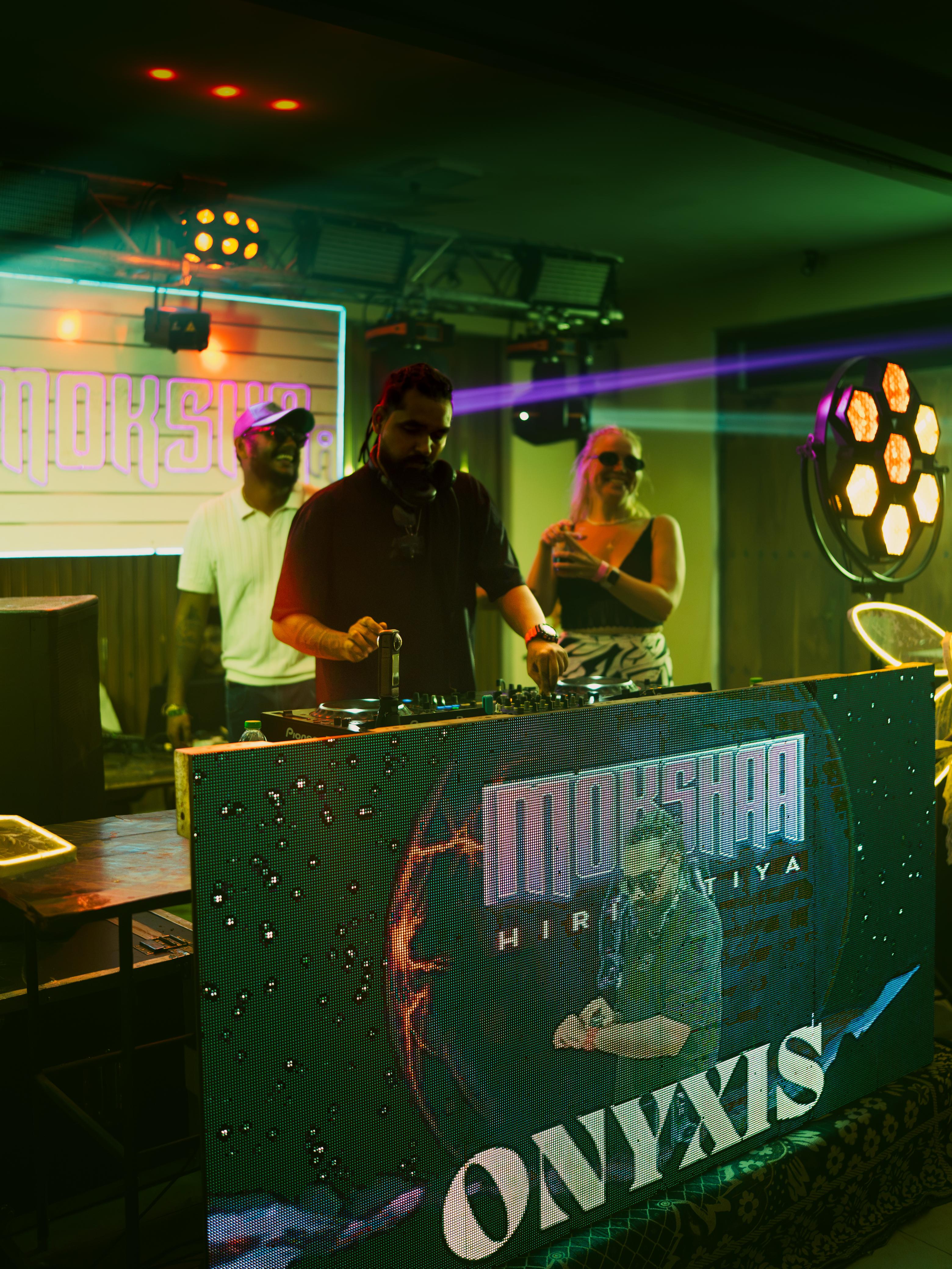 DJ performing at Mokshaa Hiriketiya with neon branding and stage lights