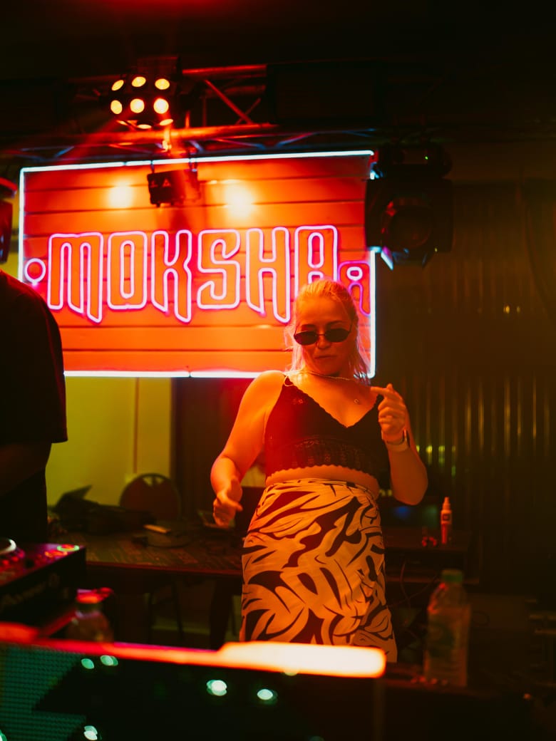 Guest dancing in front of Mokshaa neon sign Hiriketiya